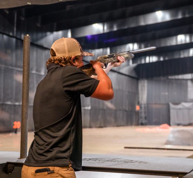 Shooting range employee shooting on an indoor shotgun shooting range